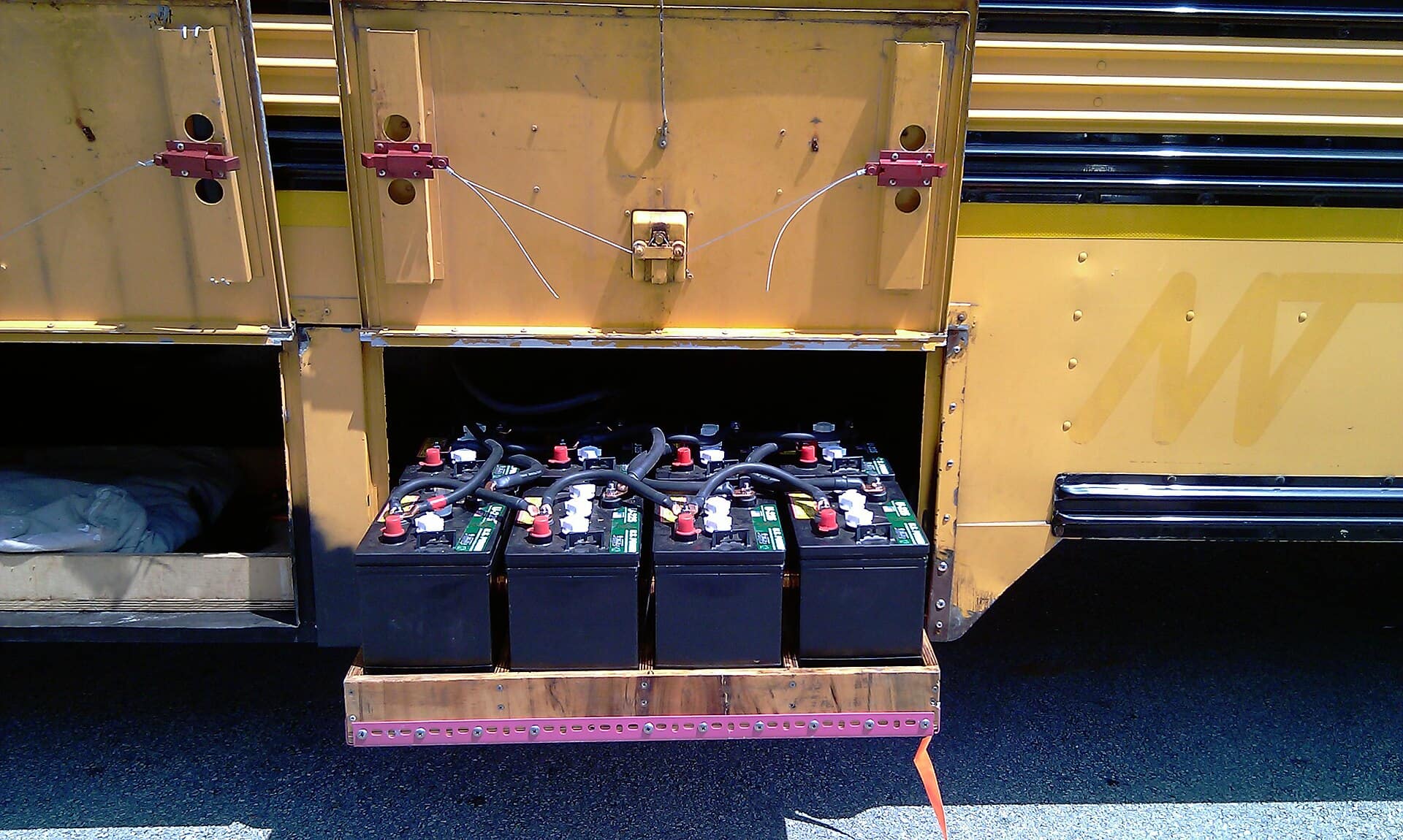 Row of four large lead-acid batteries wired together with heavy interconnects and terminal posts