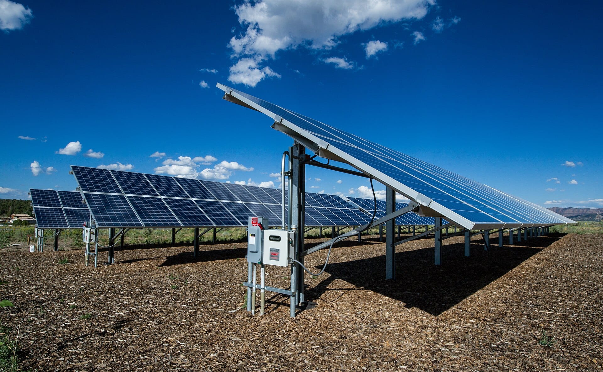 Ground-mounted solar array tilted toward the sun under a deep blue desert sky