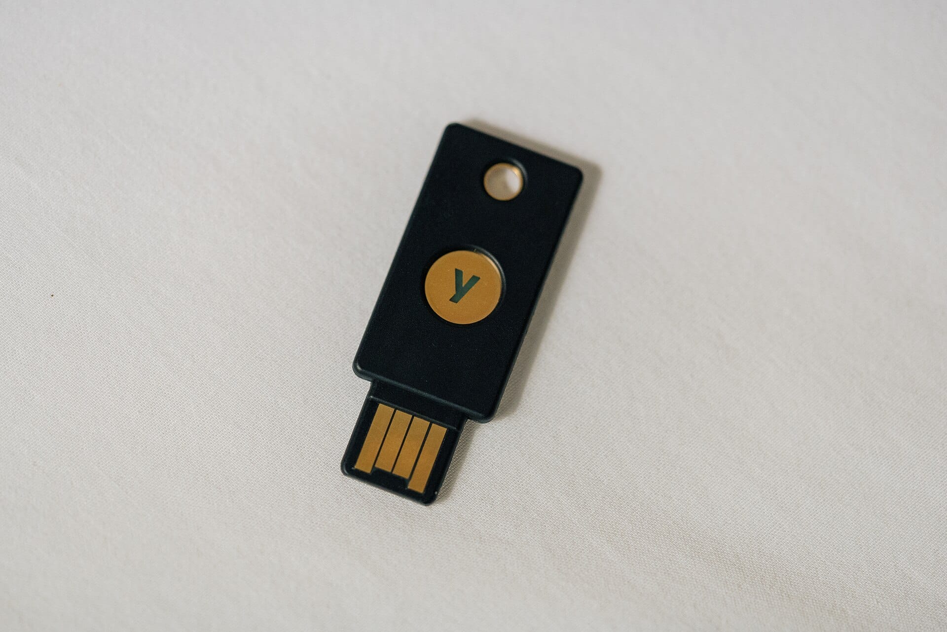 Black USB two-factor authentication security key lying on white fabric