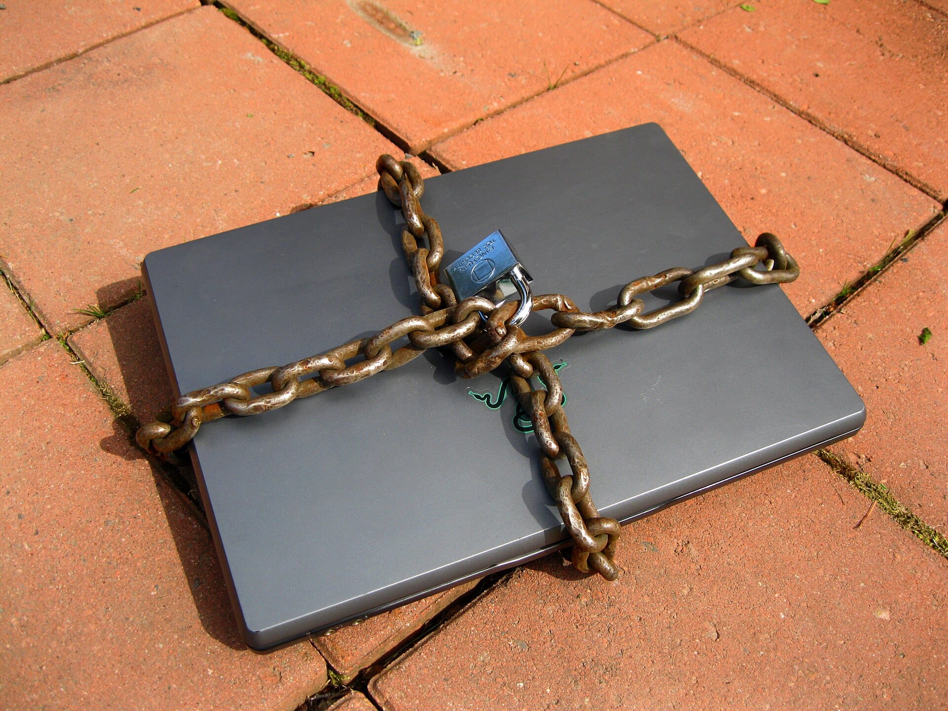 Closed laptop wrapped in a chain and padlock, a metaphor for protecting systems from hacking