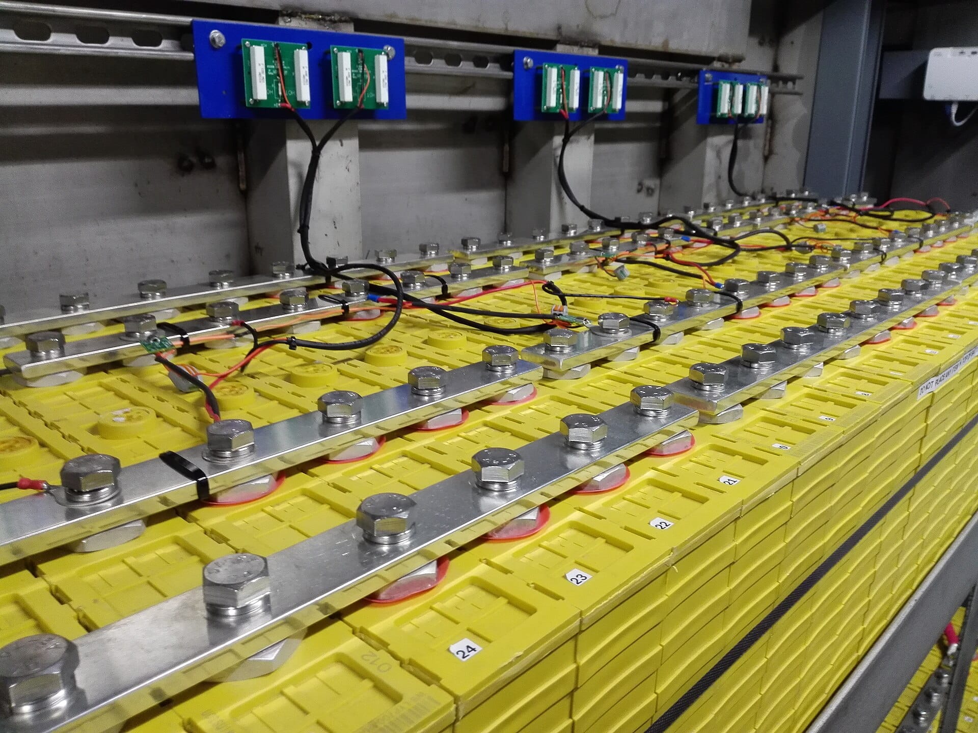 Rows of yellow lithium battery cells wired in parallel with battery packs mounted above
