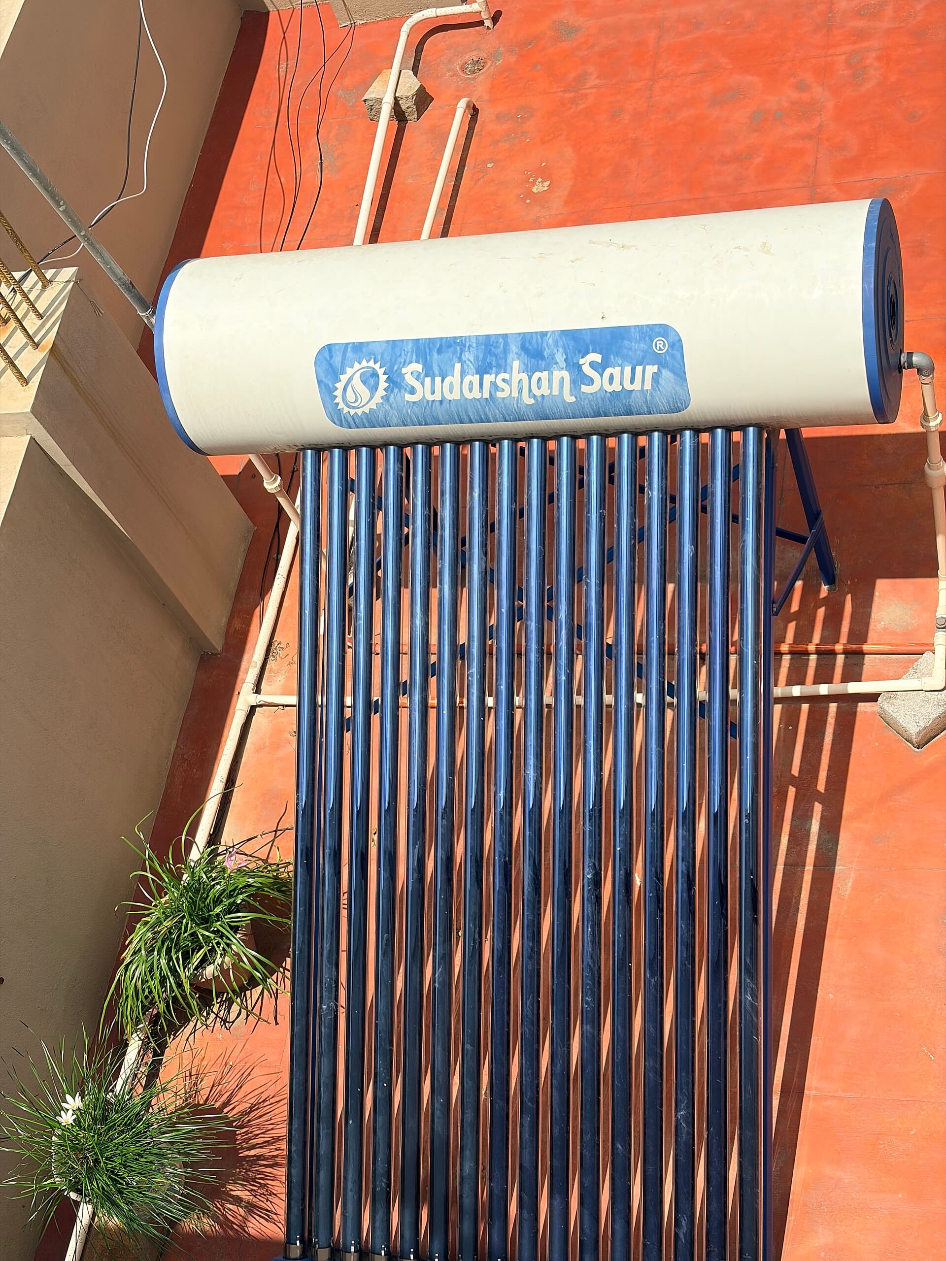 Horizontal storage tank mounted above a bank of evacuated tube collectors on a building wall