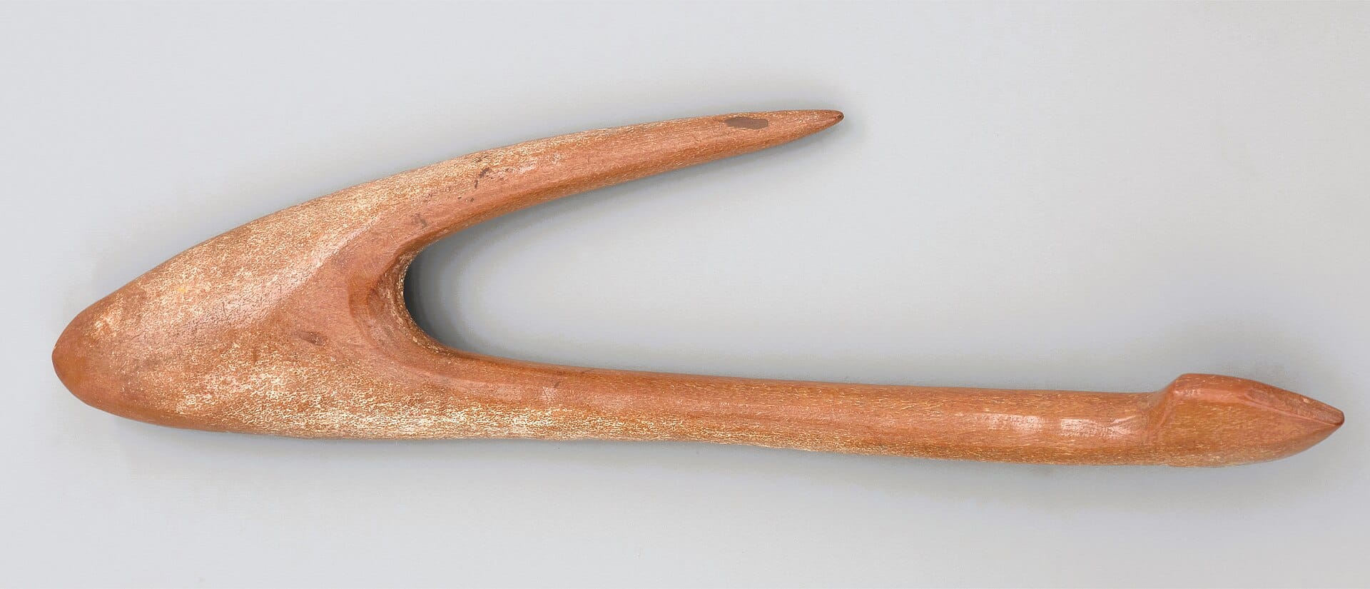 Ancient curved fishing hook photographed against a plain white background