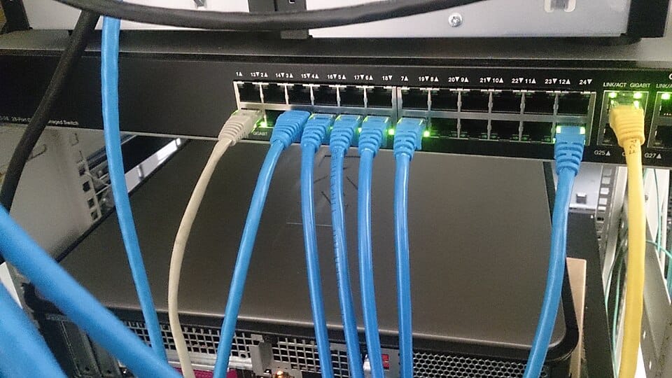 Network switch with blue Ethernet cables, the hardware that penetration testing tools scan and assess