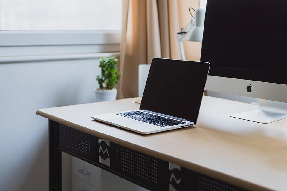 Laptop on a neat desk beside a monitor, a typical workstation for starting penetration testing